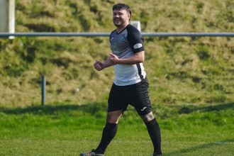 Kyle Copp smiles as he celebrates a goal for Pontardawe Town in their black-and-white kit