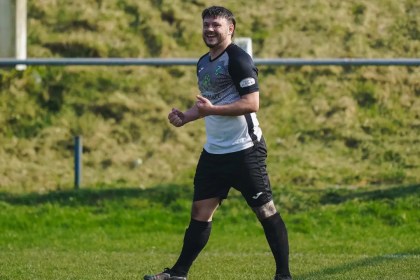 Kyle Copp smiles as he celebrates a goal for Pontardawe Town in their black-and-white kit