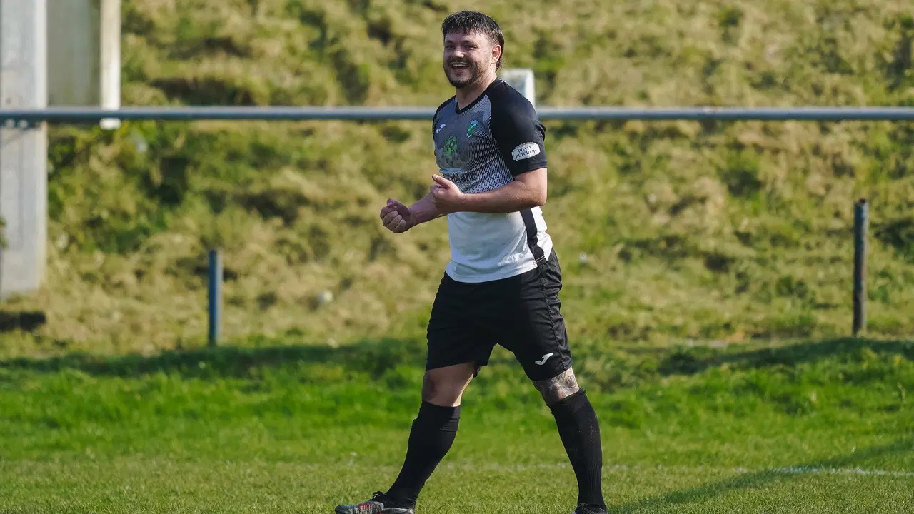 Kyle Copp smiles as he celebrates a goal for Pontardawe Town in their black-and-white kit