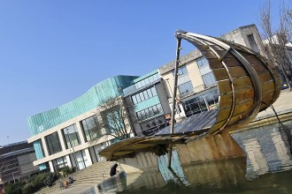 The Leaf Boat, a large curved glass and steel sculpture shaped like a leaf, beside the water feature in Swansea's Castle Square