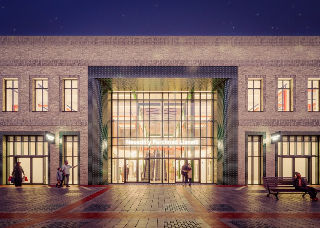 Night-time CGI render of the market hall's glazed main entrance, lit from within, with escalators and shoppers visible inside.
