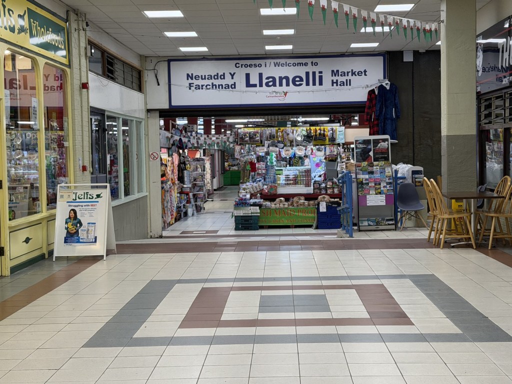 The entrance to the current Llanelli Market Hall with its bilingual Croeso i / Welcome to Llanelli Market Hall sign above stalls inside
