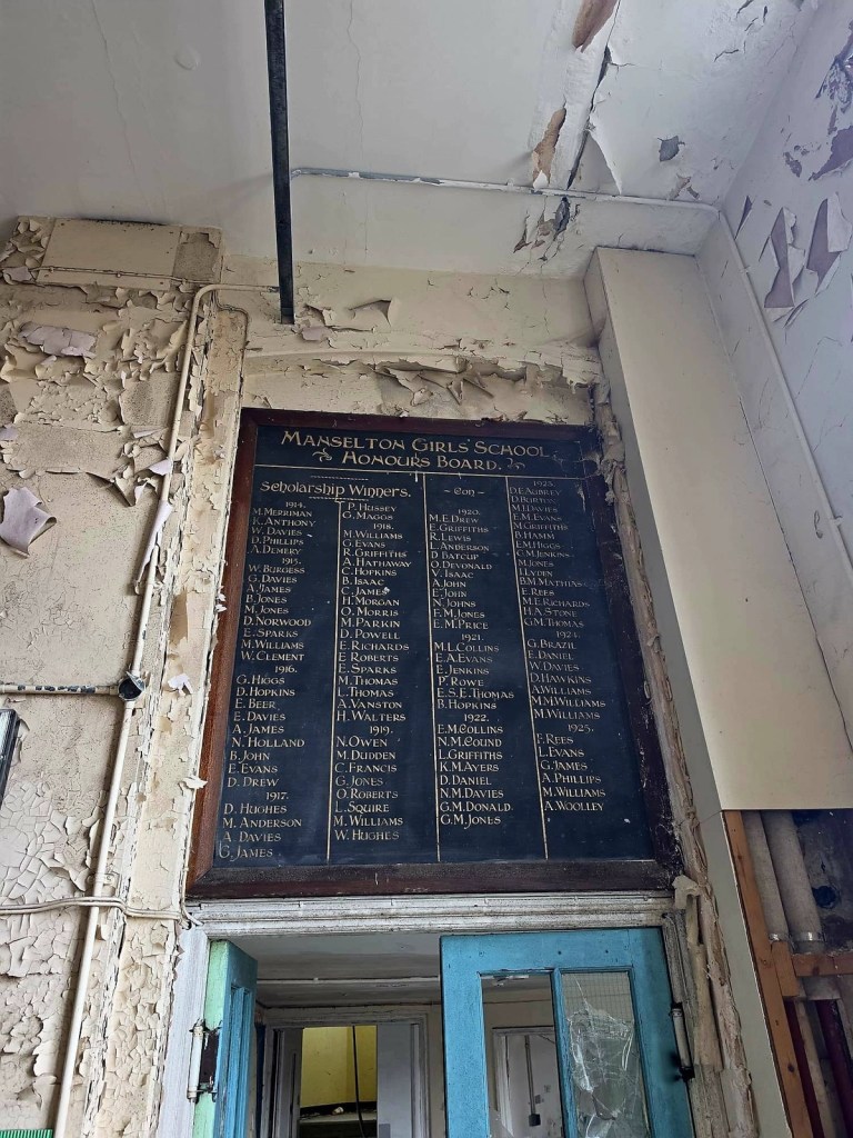 Manselton Girls' School honours board listing scholarship winners from 1914 to 1925 in gilt lettering, surrounded by peeling paint