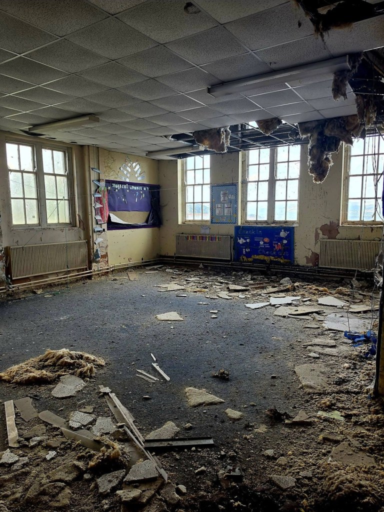 Derelict classroom with Magical Punctuation wall display, collapsed ceiling tiles and insulation hanging down