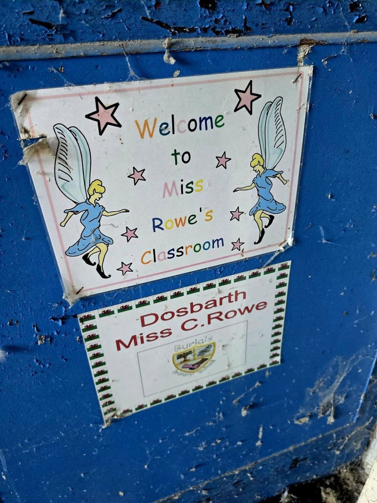 Fairy-decorated classroom welcome sign and bilingual class sign on a cobwebbed blue door