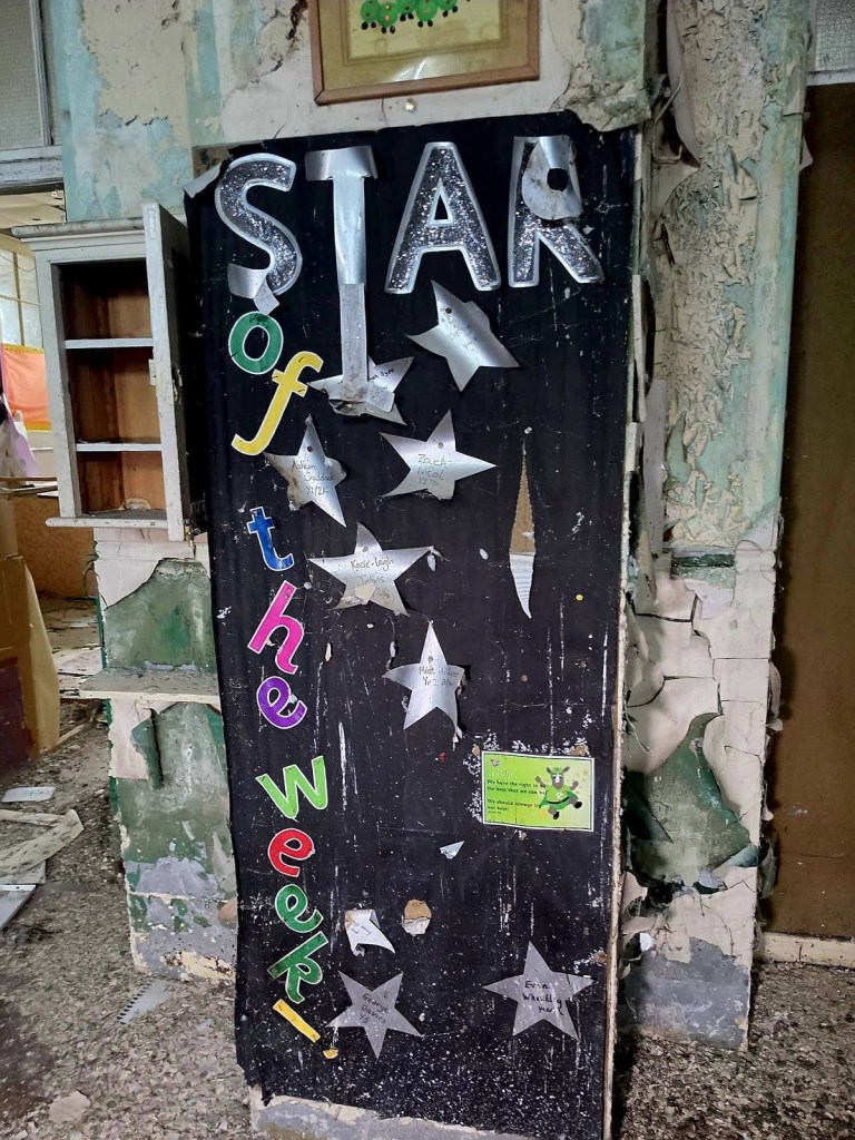 Star of the Week display board with silver hand-cut stars carrying pupils' names in a derelict school