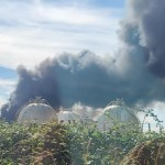 Black smoke billows behind large white spherical gas storage tanks at the Impala terminal in Milford Haven.