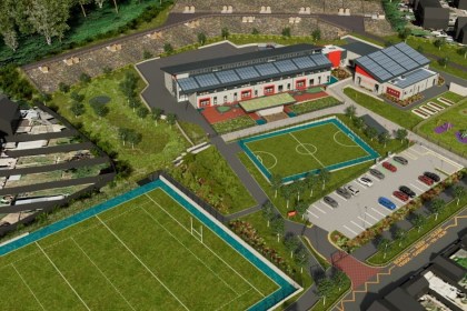 An aerial artist impression of the new Mynydd Cynffig Primary School at Kenfig Hill, showing the school building with solar panels, sports pitches, play areas and a car park