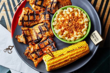 A plate of flame-grilled peri-peri chicken with macaroni cheese and corn on the cob at Nando's