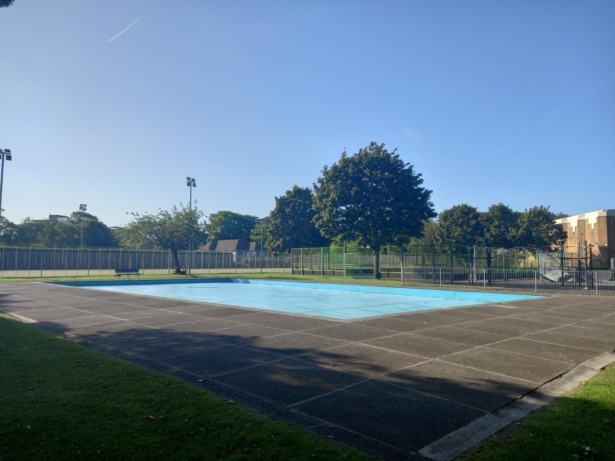 The paddling pool at Peoples' Park, Llanelli, with a play area and skate park behind