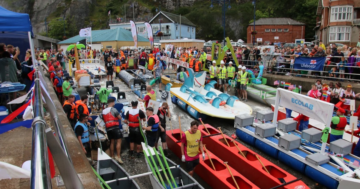 Colourful homemade rafts and crews in fancy dress at the Knab Rock slipway, with crowds watching behind