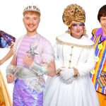 Six pantomime cast members in costume against a white background — the Wicked Queen in a black gown holding a red apple, Snow White in a blue and gold dress, the Spirit of the Forest in a silver crown, a dame in a white sequinned gown and gold bow, a comic in a striped waistcoat, and a henchman in a zebra-print coat.