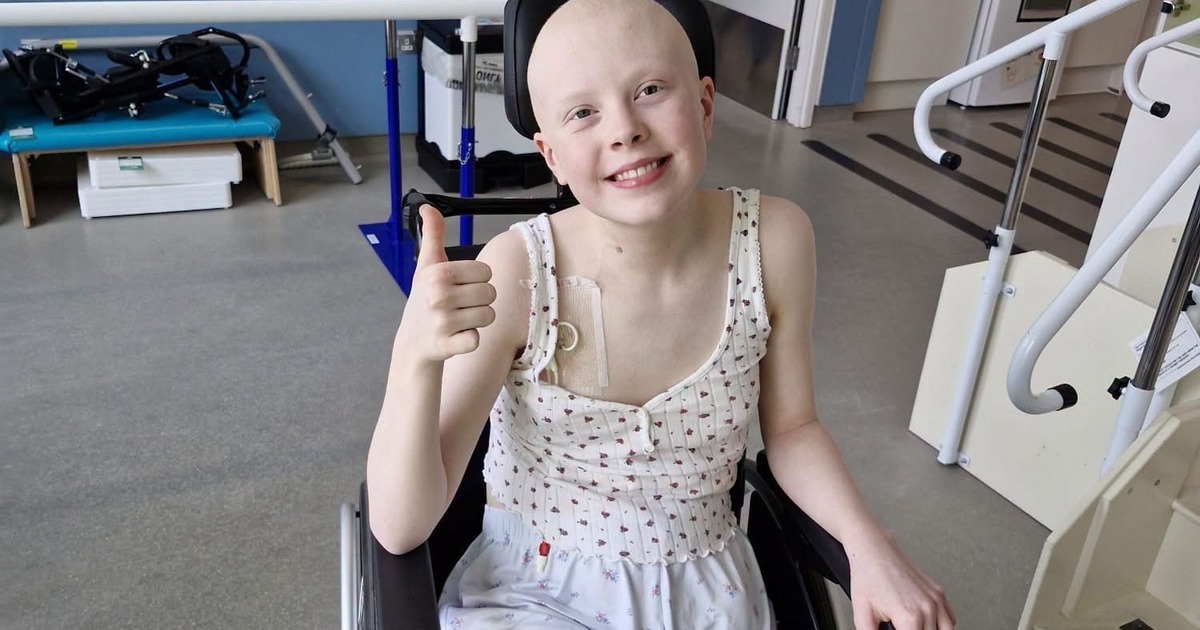 Soffia smiling and giving a thumbs up from her wheelchair in a hospital rehabilitation room