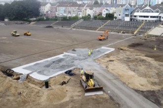 Aerial view of St Helen's with the pitch stripped to bare earth, drainage stone laid in a cross, and empty terracing behind