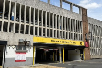 The multi-storey Kingsway car park with a yellow NCP Welcome to Kingsway Car Park sign above the entrance and a red Swansea Council sign and tariff board on the wall below