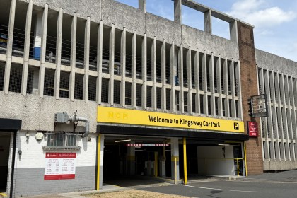 The multi-storey Kingsway car park with a yellow NCP Welcome to Kingsway Car Park sign above the entrance and a red Swansea Council sign and tariff board on the wall below