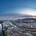 Aerial view of Swansea city centre at dusk, with the River Tawe, railway lines into High Street station, new riverside housing and Kilvey Hill