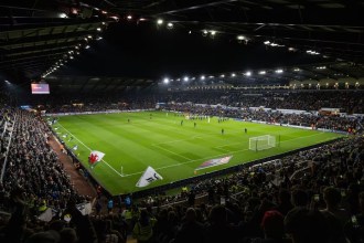 A packed Swansea.com Stadium under floodlights as the teams walk out for Swansea City's match against Manchester City in October 2025