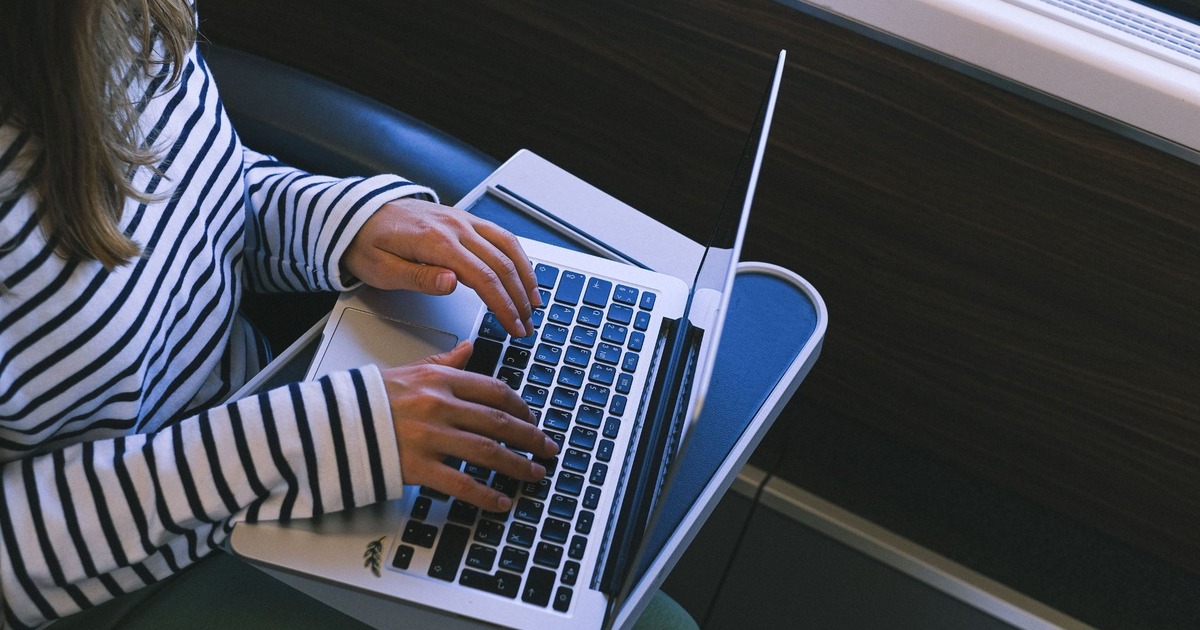 A person working on a laptop at a train table during a journey