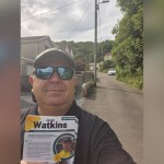 Jamie Watkins in sunglasses and a cap takes a selfie on a Trebanos street holding a bundle of his Plaid Cymru campaign leaflets