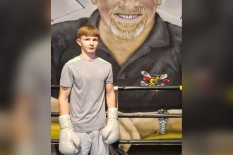 Tyler Ford, an 18-year-old with short light brown hair, standing in a boxing gym wearing grey boxing gloves.
