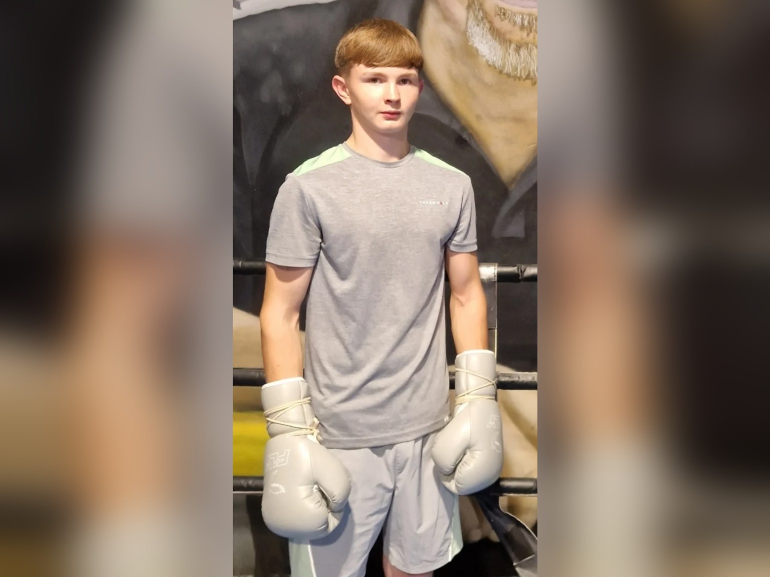Tyler Ford, an 18-year-old with short light brown hair, standing in a boxing gym wearing grey boxing gloves.