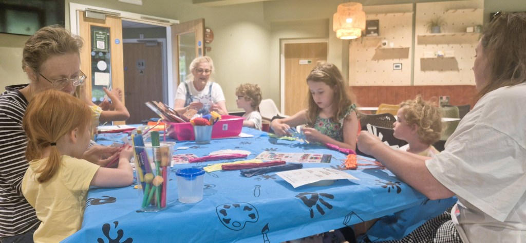 Adults and children making crafts around a long table at Underhill Hub in Mumbles