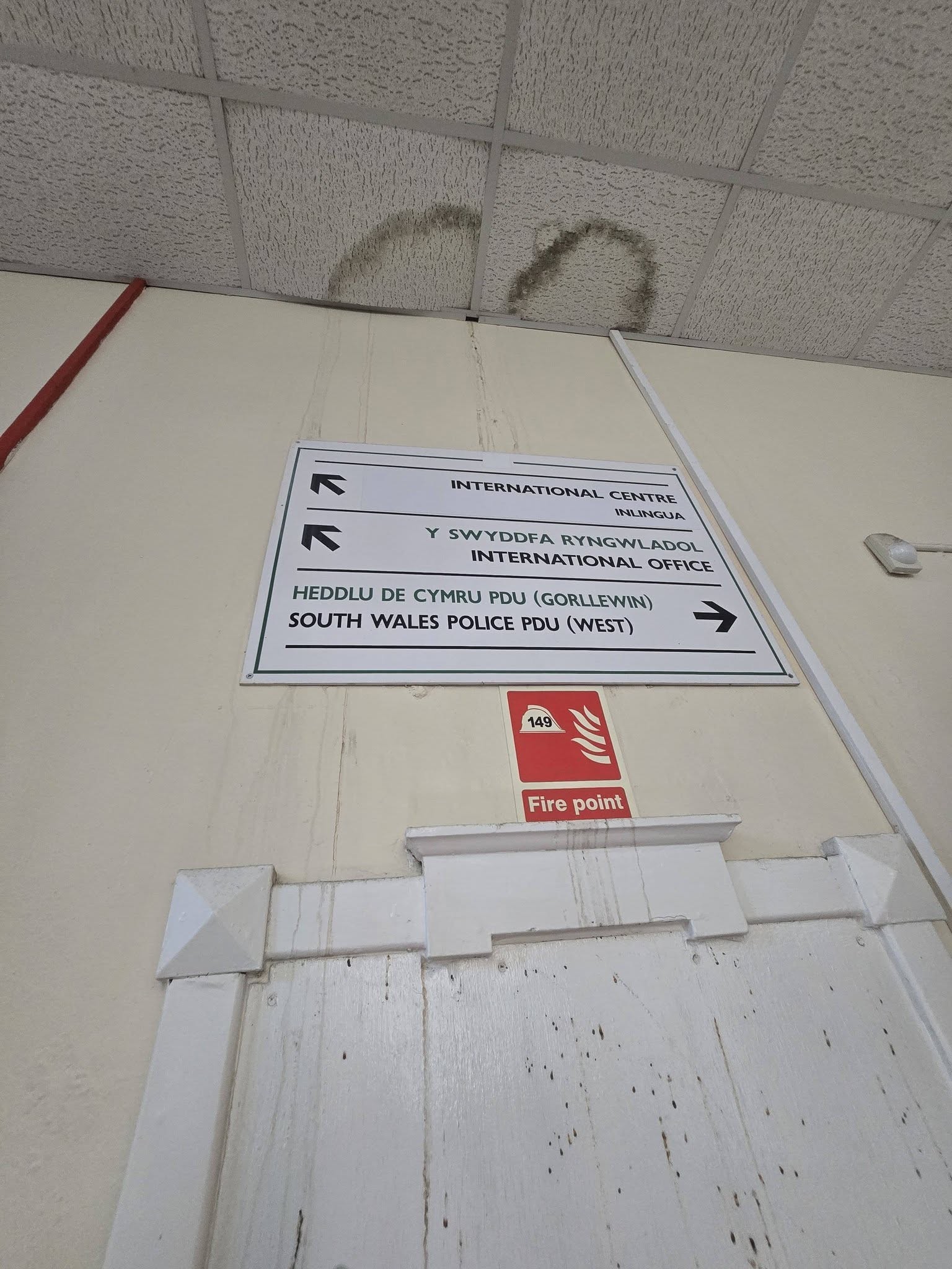 Bilingual direction sign pointing to the International Centre and South Wales Police PDU West