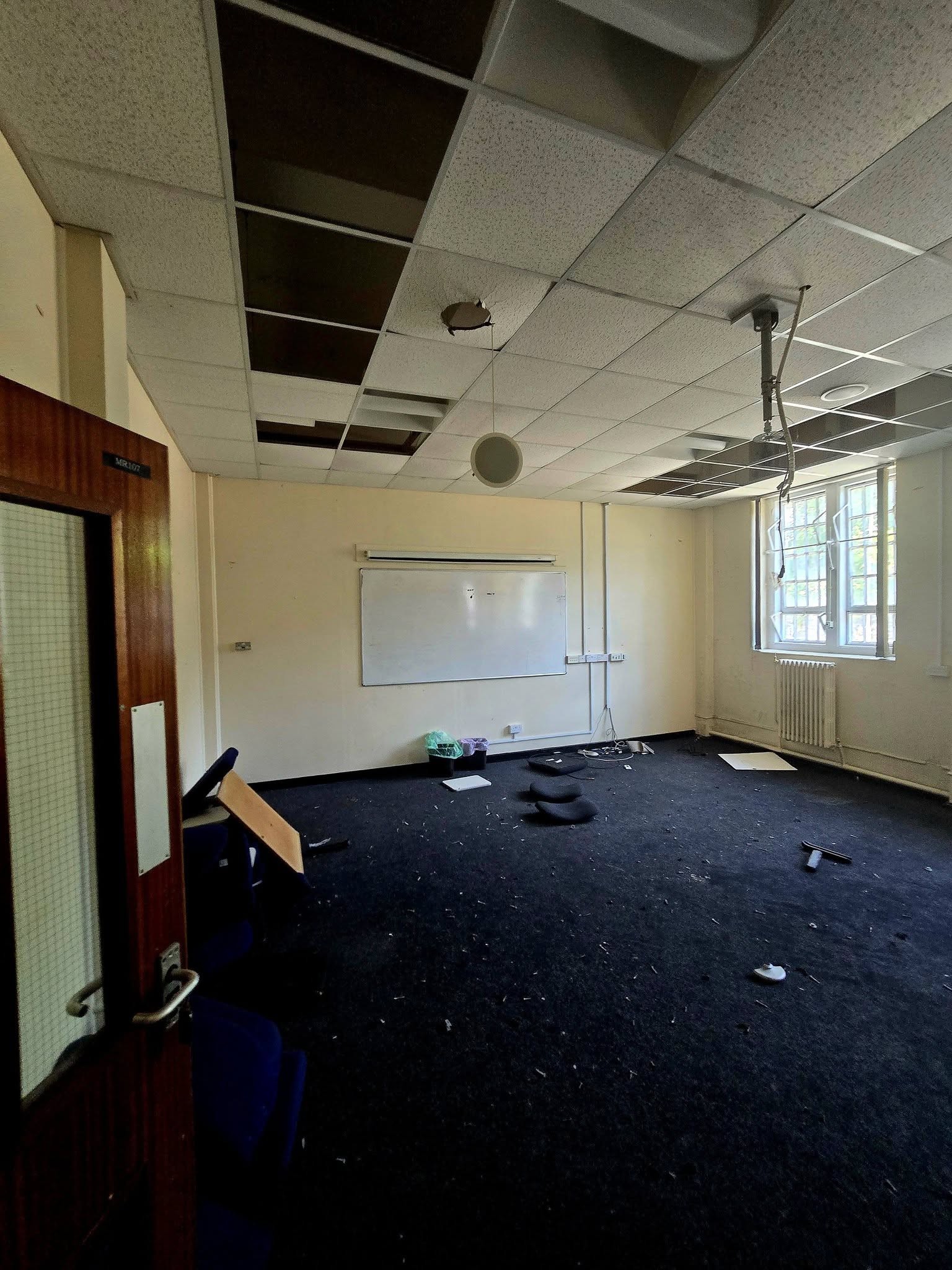 Empty classroom MR107 with whiteboard and projector mount hanging from ceiling grid