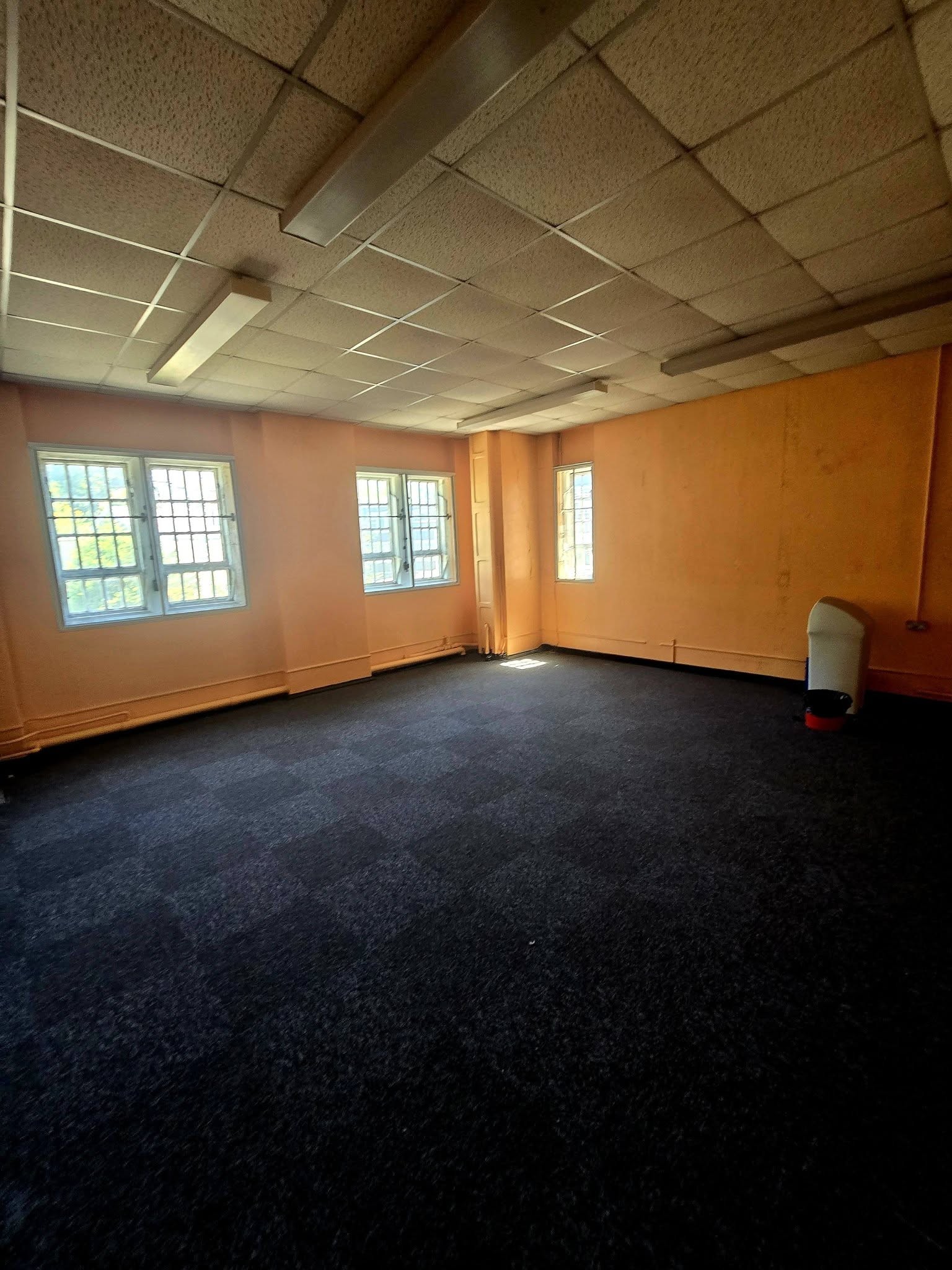 Empty classroom with orange walls dark carpet tiles and leaded windows