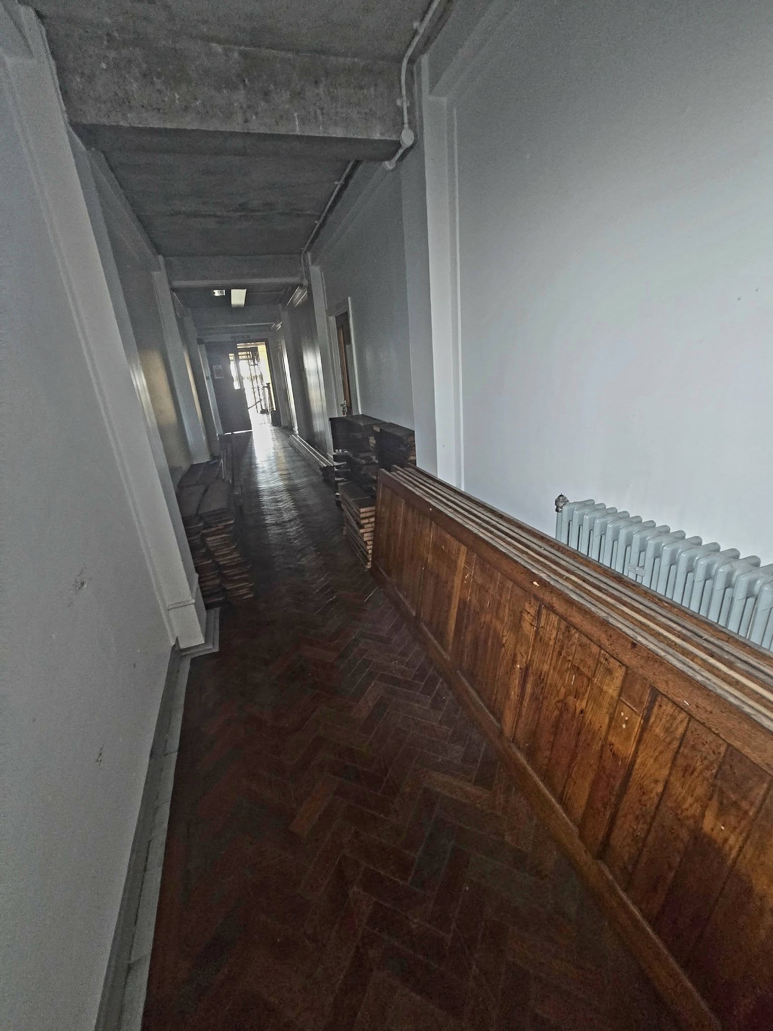 Herringbone parquet corridor with oak panelling and stacked wooden flooring