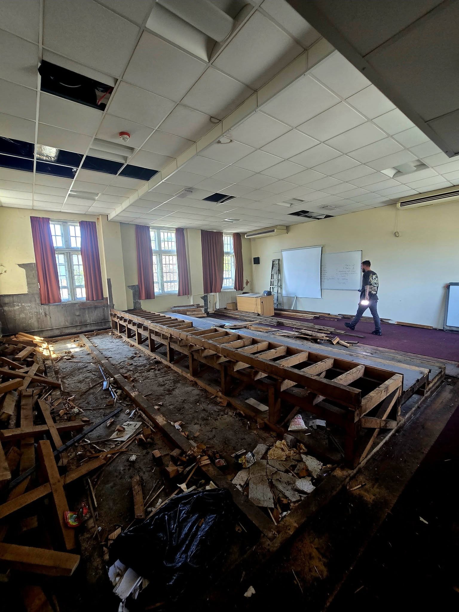 Lecture theatre stripped back to timber tiers with debris on the floor