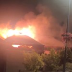 Flames and smoke rising from the roof of Verdi's cafe in Mumbles at night, seen from Mumbles Road