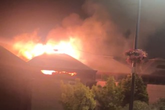 Flames and smoke rising from the roof of Verdi's cafe in Mumbles at night, seen from Mumbles Road