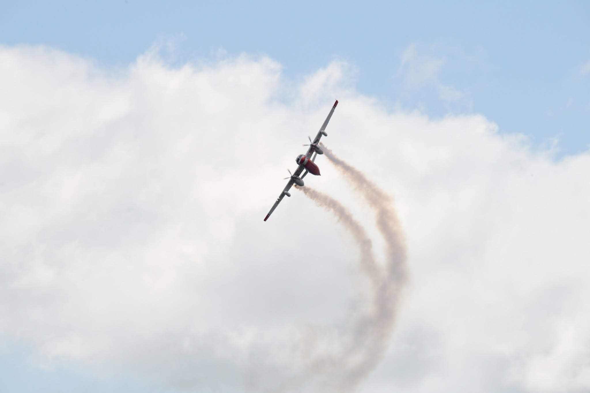 A Firecat water bomber climbing steeply with a curved smoke trail behind it