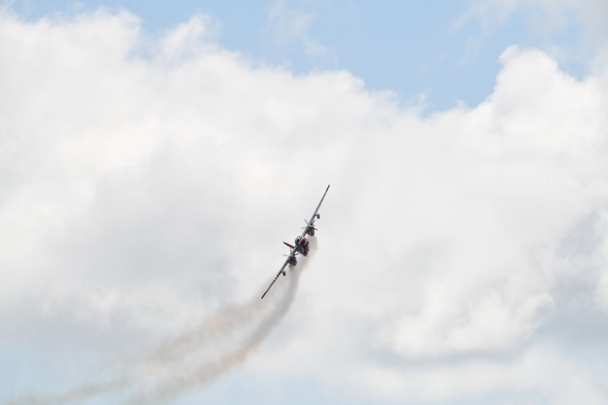 A Firecat water bomber in a steep climbing turn against white cloud