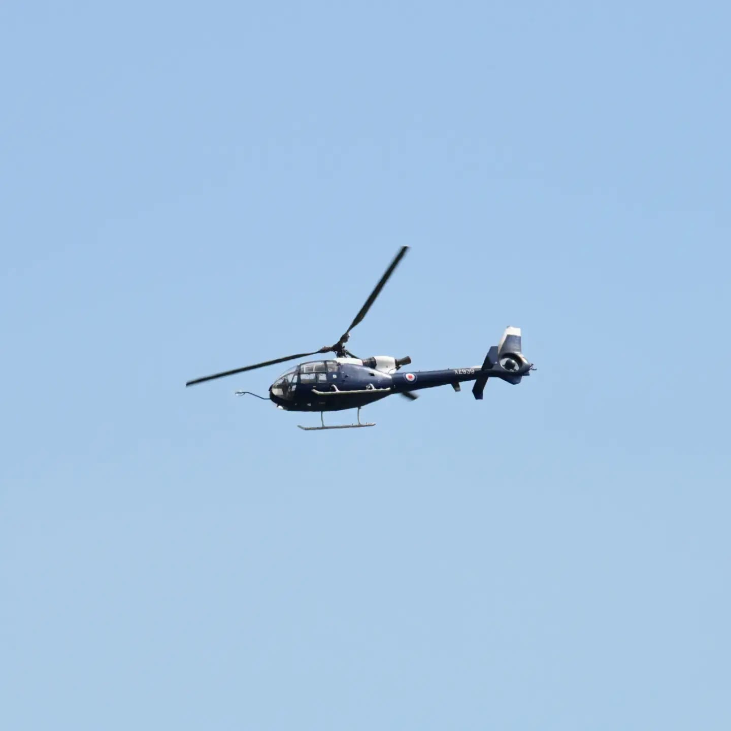 A Westland Gazelle helicopter banking against a clear blue sky