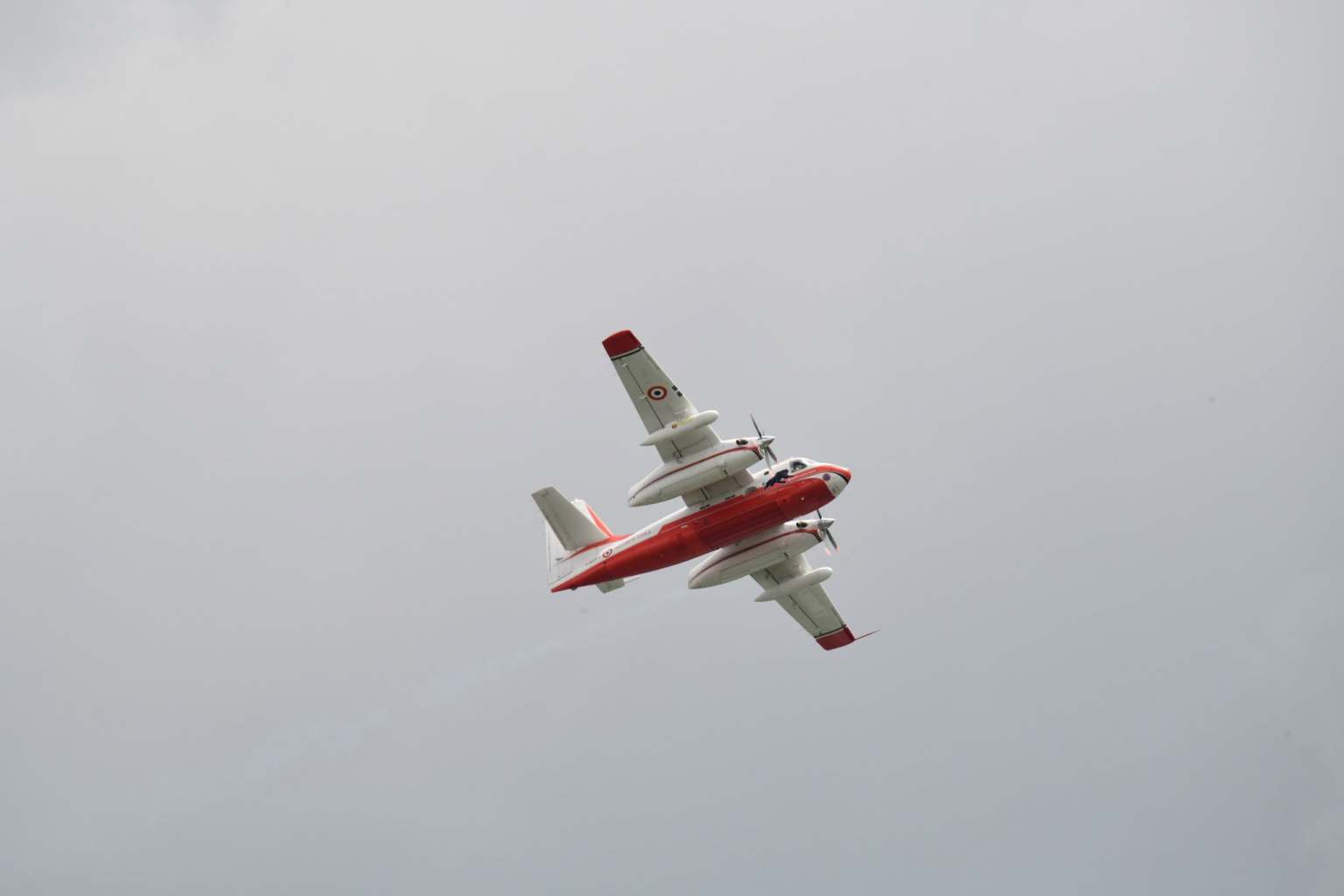 A red and white Grumman Firecat water bomber in French Sécurité Civile markings banking over Swansea Bay