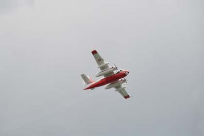A red and white Grumman Firecat water bomber in French Sécurité Civile markings banking over Swansea Bay