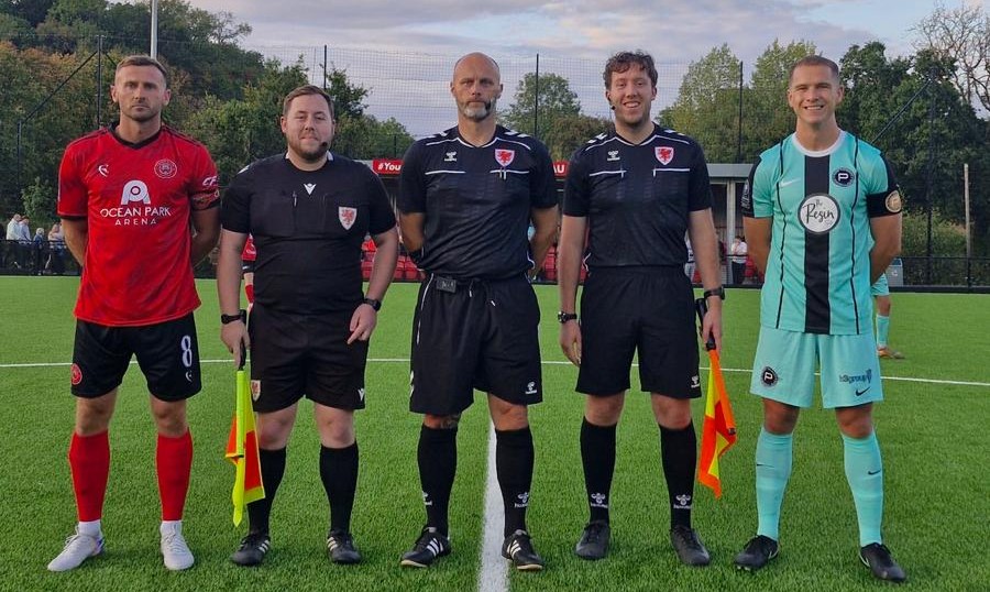 The Caerau Ely and Pure Swansea captains standing either side of the three match officials before kick-off
