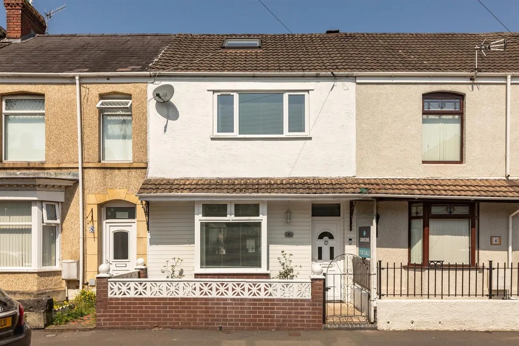 A white painted mid terrace house on Alexandra Terrace with a Dawsons for sale board outside