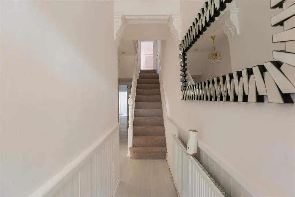 A hallway with original cornicing above the stairs and a large mirror on the wall