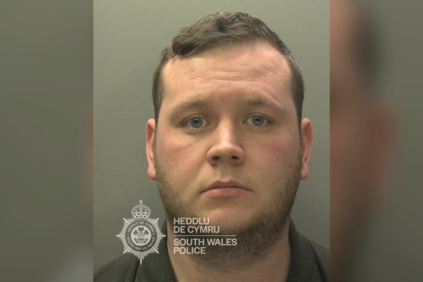 South Wales Police custody image of Ashley John, a man with short dark hair, on a grey background with the force's bilingual watermark