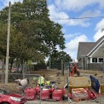 Metal fencing, a cement mixer, bulk bags and a mini digger on bare ground at the entrance to Ysgol Bancyfelin