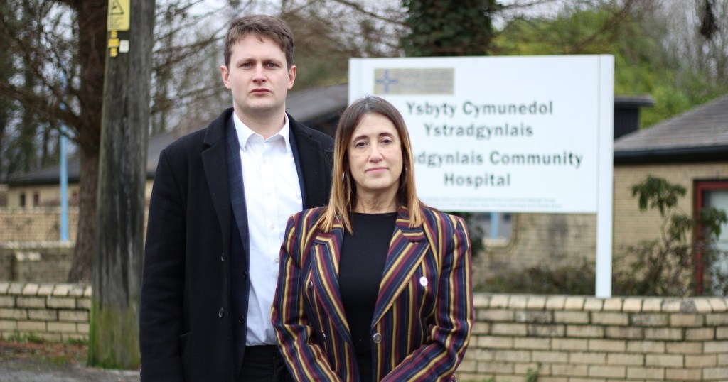 David Chadwick MP and Jane Dodds MS standing in front of the bilingual Ystradgynlais Community Hospital sign
