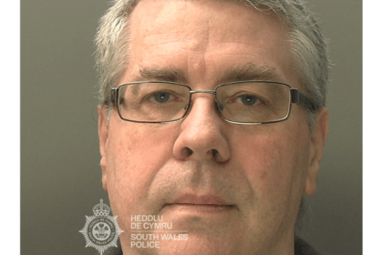 Police custody photograph of Christopher Phillips, a man in his sixties with grey hair and glasses, wearing a dark jumper