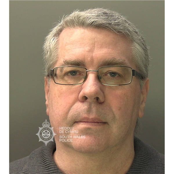 Police custody photograph of Christopher Phillips, a man in his sixties with grey hair and glasses, wearing a dark jumper