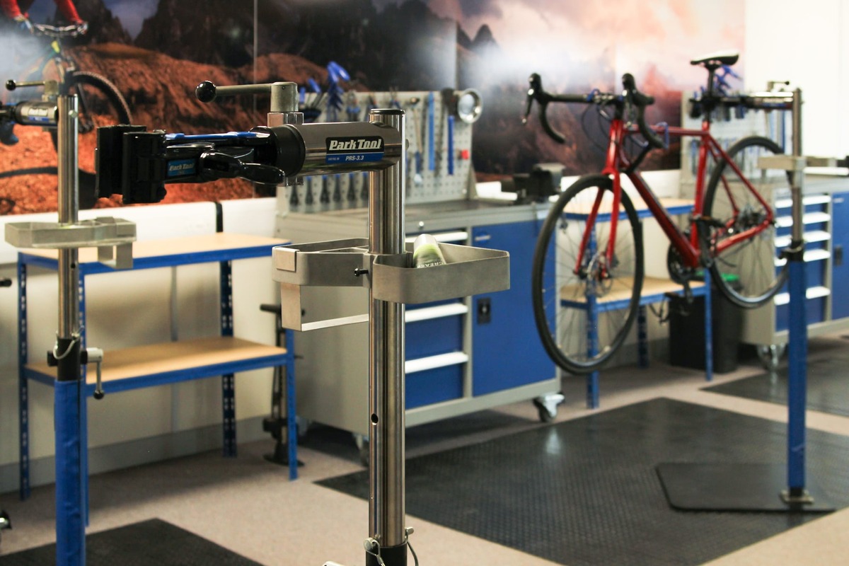 The Cycle CPD training workshop with repair stands, blue tool benches and a red road bike mounted on a stand