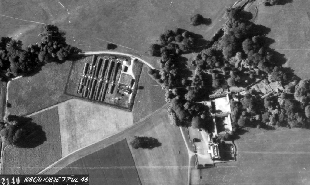 Black and white aerial photograph showing rows of Nissen huts beside parkland