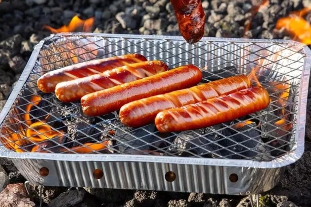 Sausages cooking on a disposable barbecue